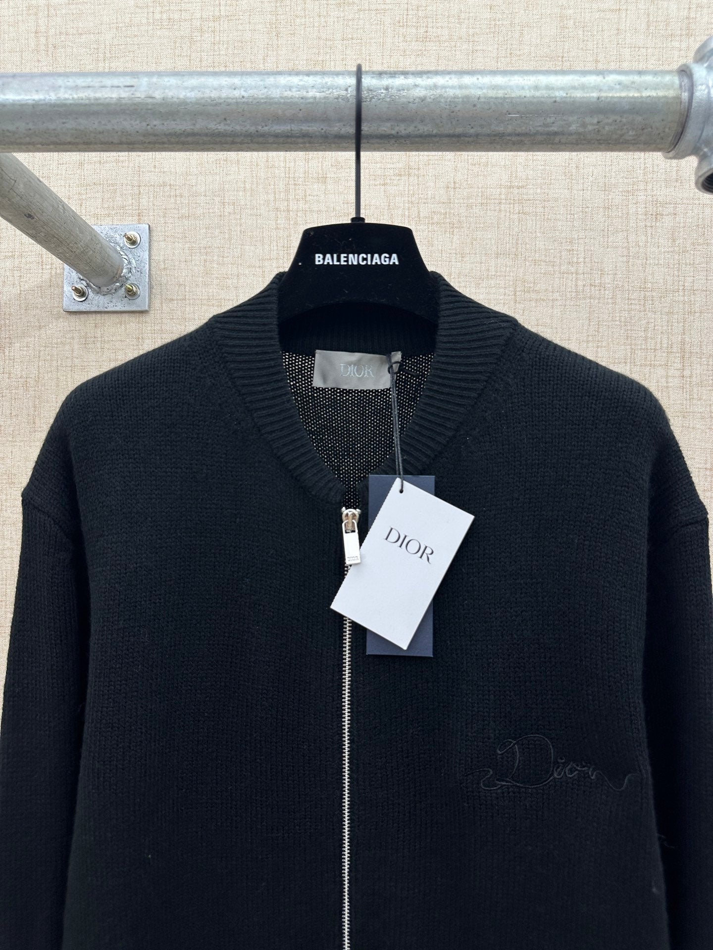 Dark zip-up knit jacket with ribbed stand collar and front hang tags