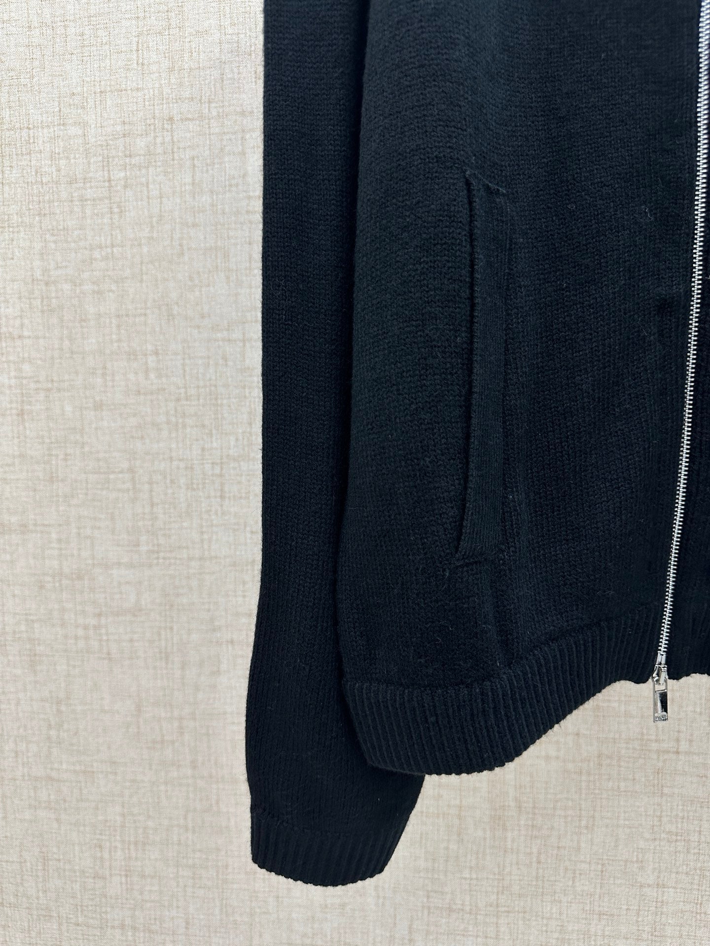 Dark knit jacket side view with ribbed hem and zipper at the edge