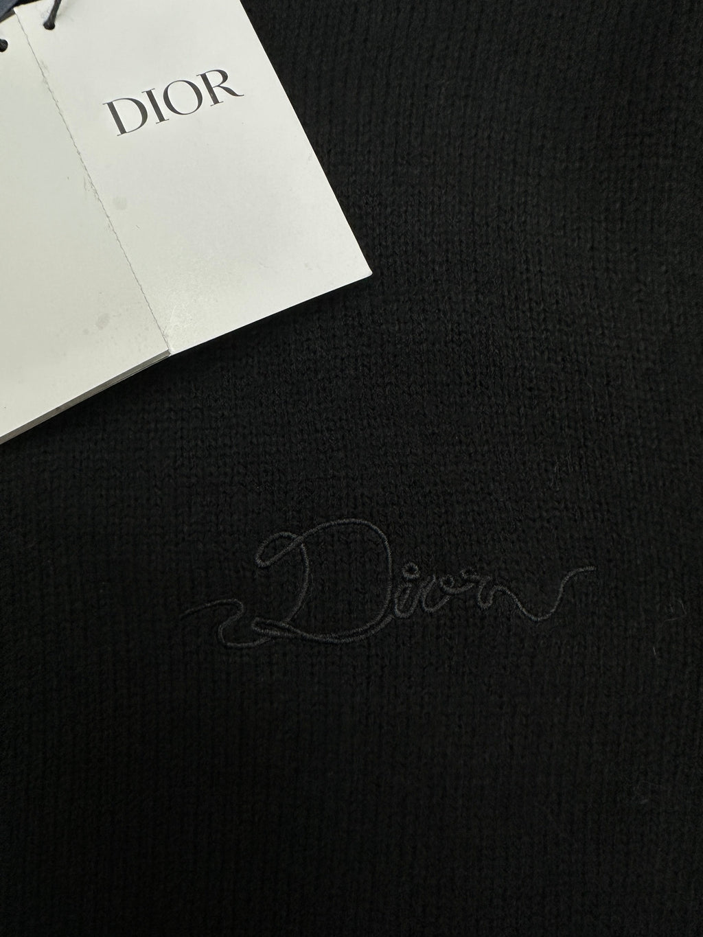 Dark knit fabric with embroidered signature and attached Dior hang tags