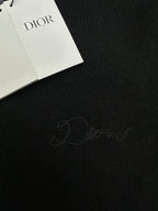 Dark knit fabric with embroidered signature and attached Dior hang tags