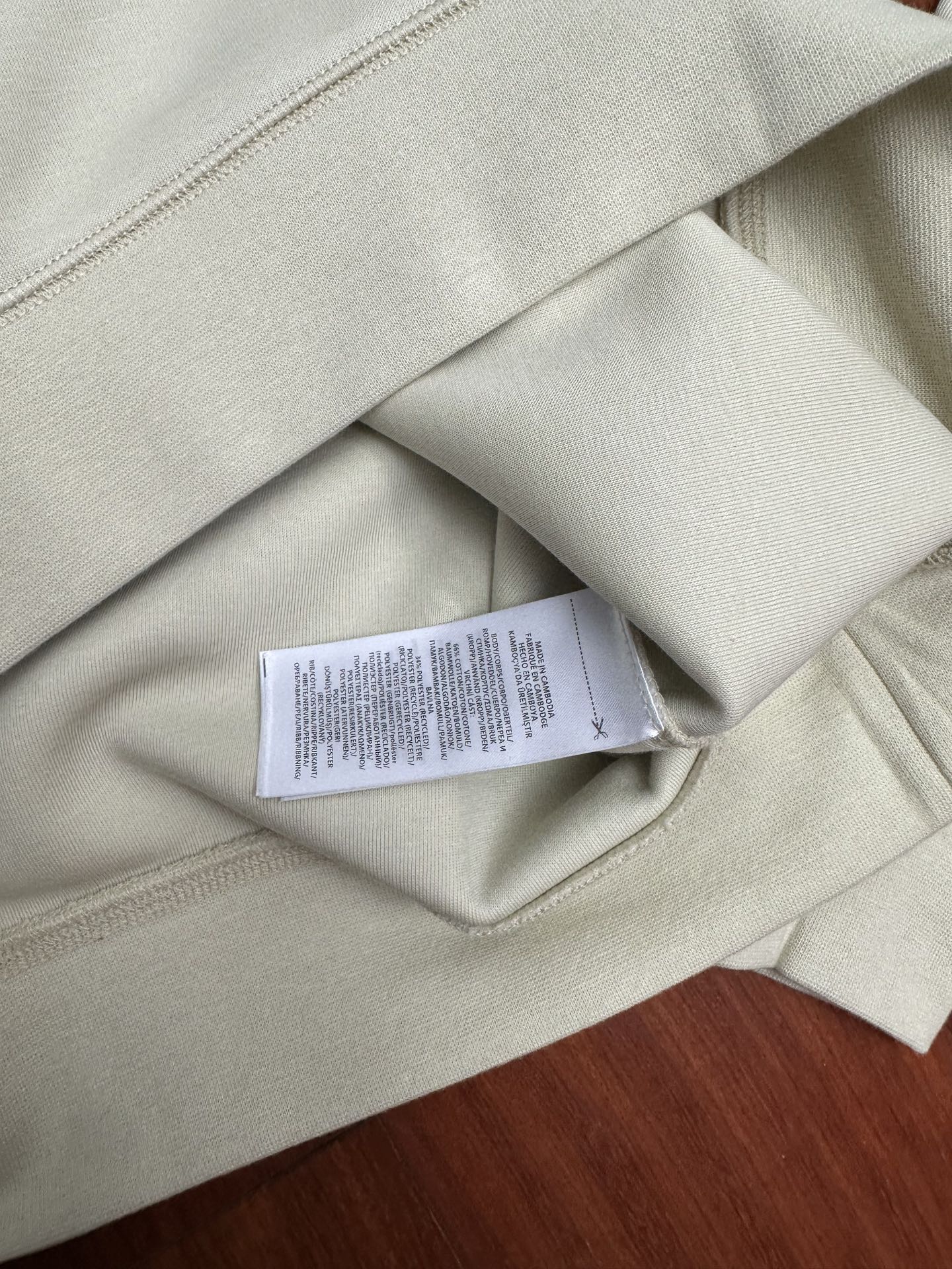 Cream sweatshirt with care label visible at interior neck seam