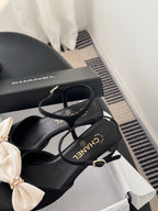 Black bow sandals with thin ankle straps and gold-tone Chanel logo on footbeds