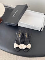 Black bow sandals with gold-tone ankle buckle and Chanel logo on straps