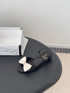 Black bow slide sandals with gold-tone Chanel logo detail and buckle strap