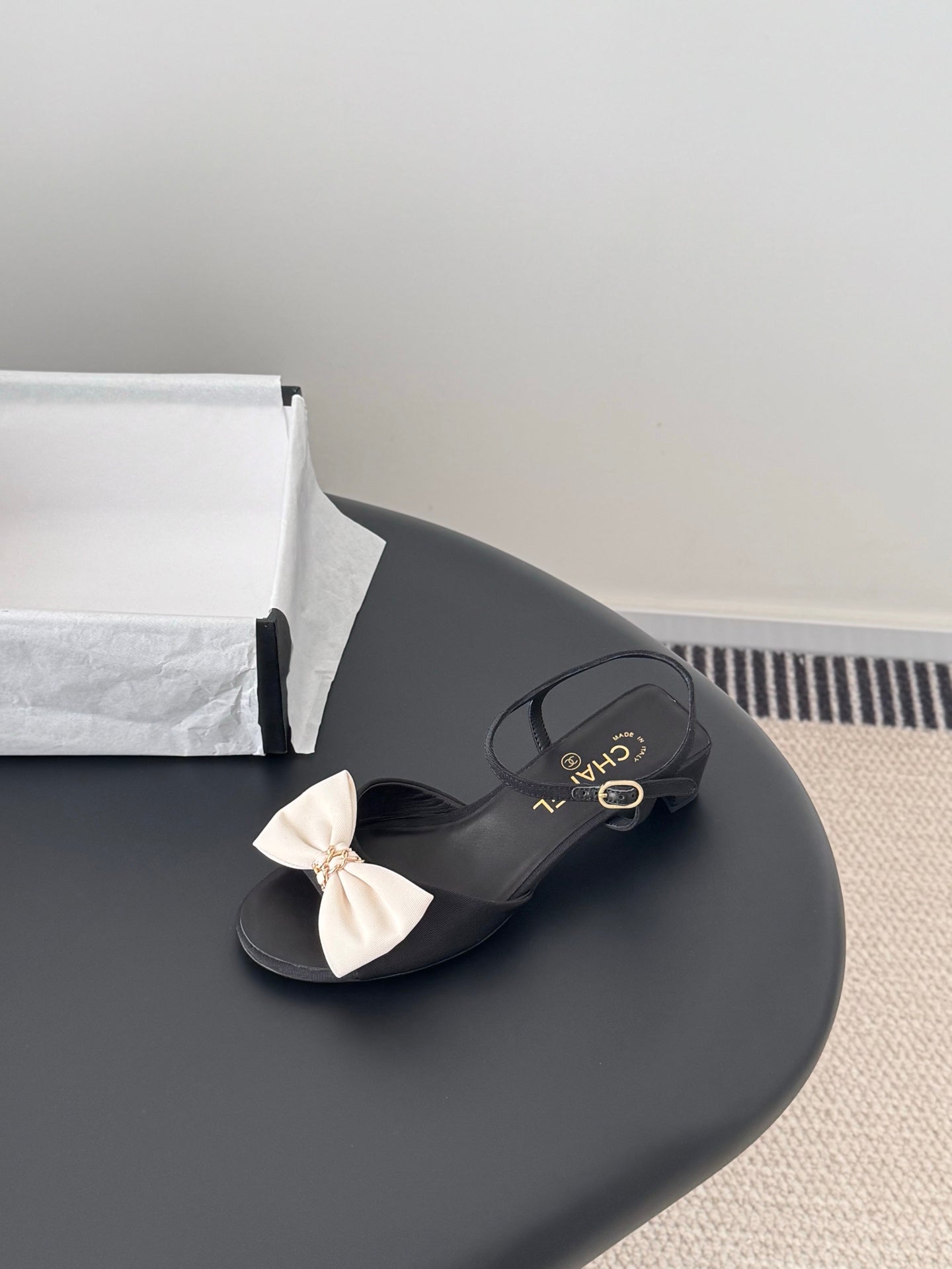 Black bow slide sandals with gold-tone Chanel logo detail and buckle strap