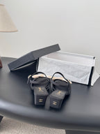 Pair of black bow sandals with ankle straps and gold-tone Chanel logos