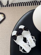 Chanel bow sandals, white straps with black knot bow and gold charm, ankle strap