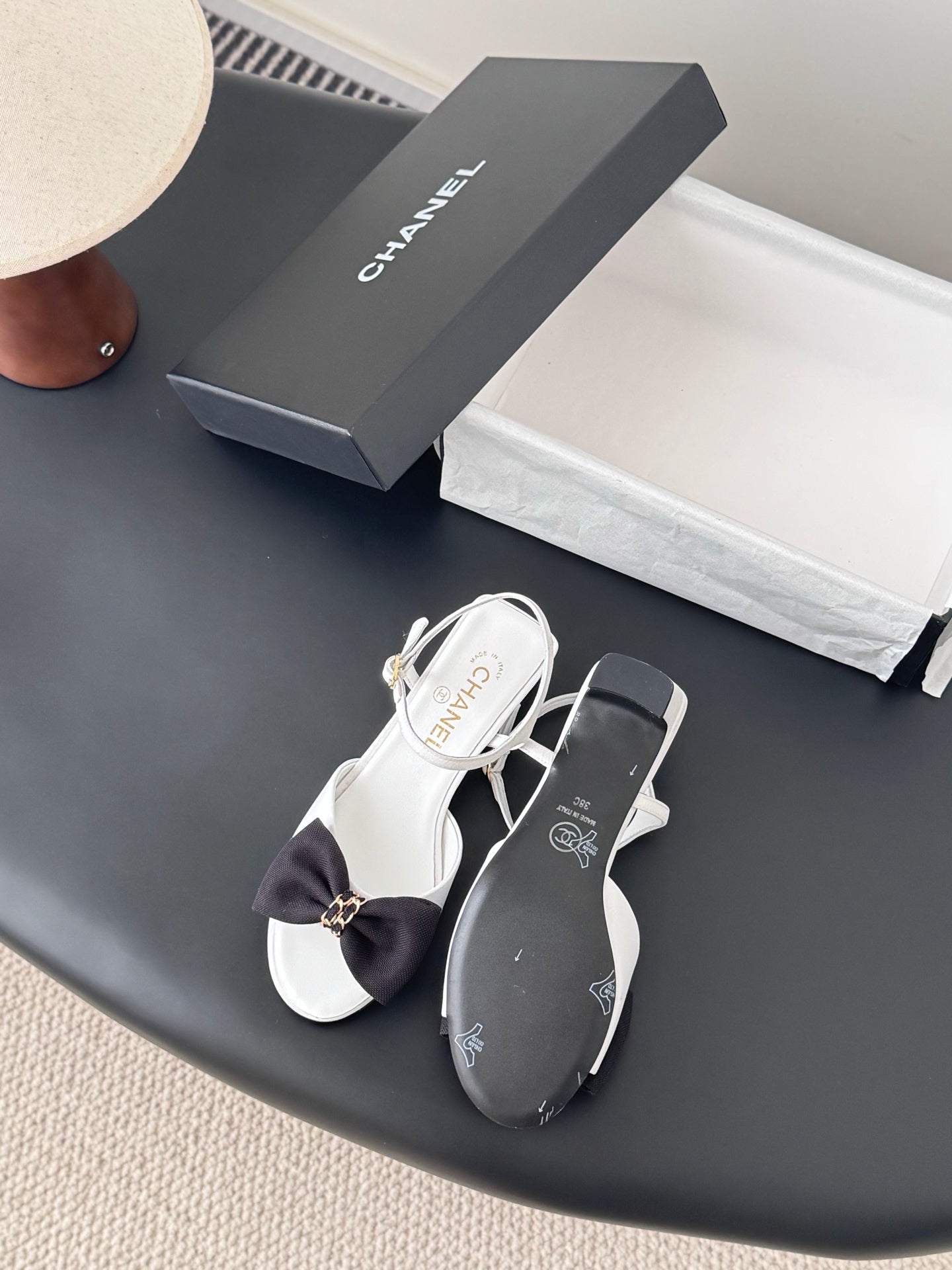 Chanel bow sandals in white with black bow accents and gold buckle, open toe