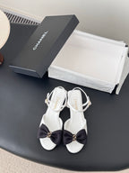 Chanel bow sandals in white with black satin knot and gold buckle, ankle strap