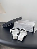 Pair of white slingback sandals with dark bow, gold-tone heel strap details