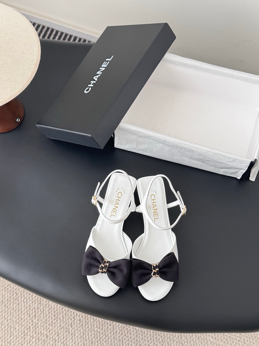 White open-toe sandals with dark bow and gold-tone ankle buckle, slingback strap