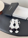 White open-toe sandals with dark bow and gold-tone ankle buckle, slingback strap