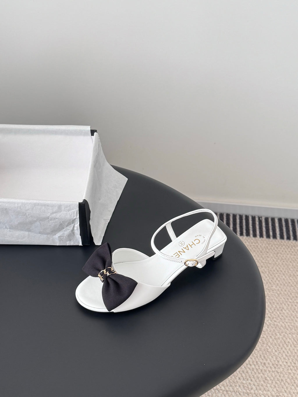 White sandals with dark bow at vamp and white ankle strap, open toe