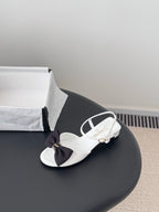 White sandals with dark bow at vamp and white ankle strap, open toe