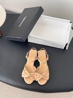 Beige satin bow sandals with ankle straps and low block heels