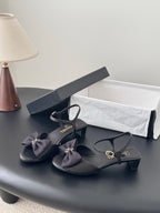 Chanel women's dark heeled sandals with ankle strap and bow detail, gold hardware