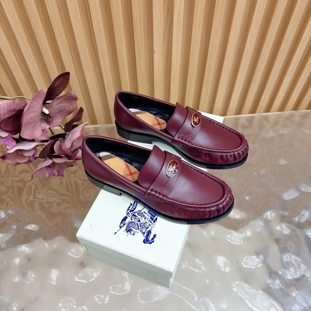 Burgundy leather loafers with gold crest and plaid lining, pair side view