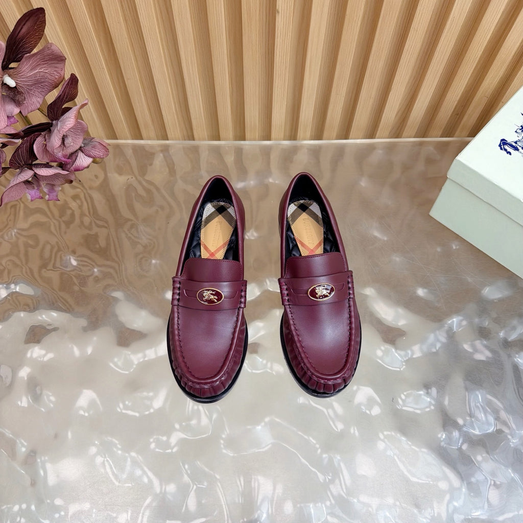 Burgundy leather penny loafers with gold crest and plaid lining, front view pair