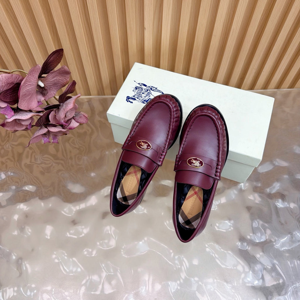 Burgundy leather loafers with gold crest and plaid lining, top view of pair