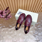 Burgundy leather loafers with gold crest and plaid lining, top view of pair