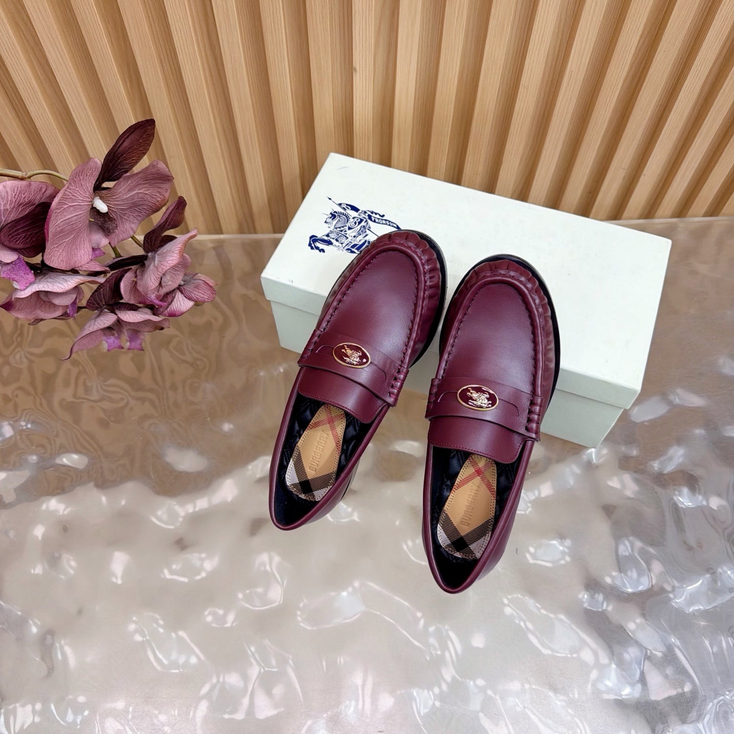 Burgundy leather loafers with gold crest and plaid lining, top view of pair