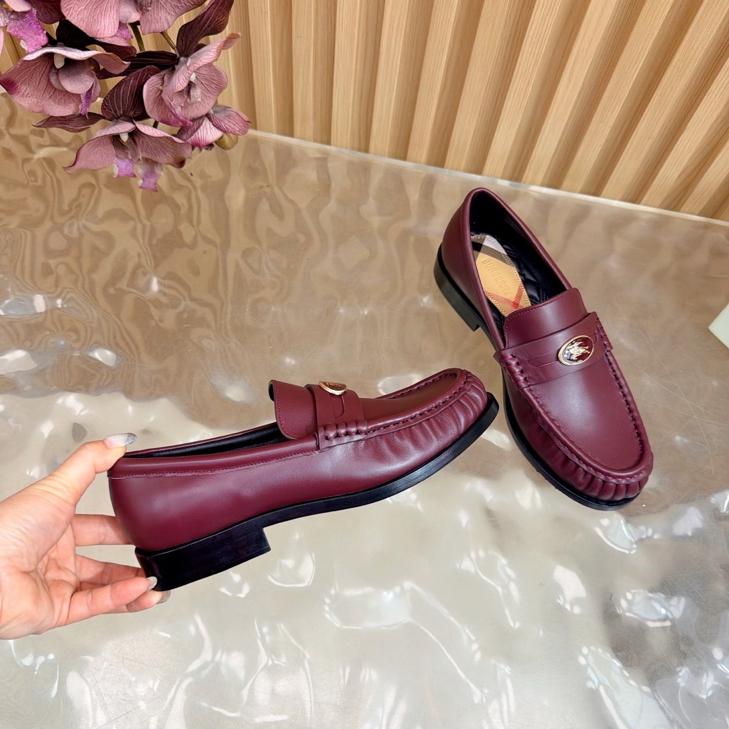 Burgundy leather loafer with gold crest and plaid lining, side and sole view
