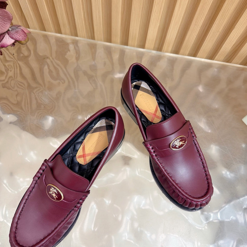 Burgundy leather loafers with gold crest and plaid lining, tilted front pair view