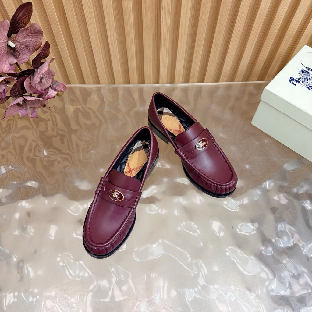 Burgundy leather loafers with gold crest and plaid lining, angled pair view