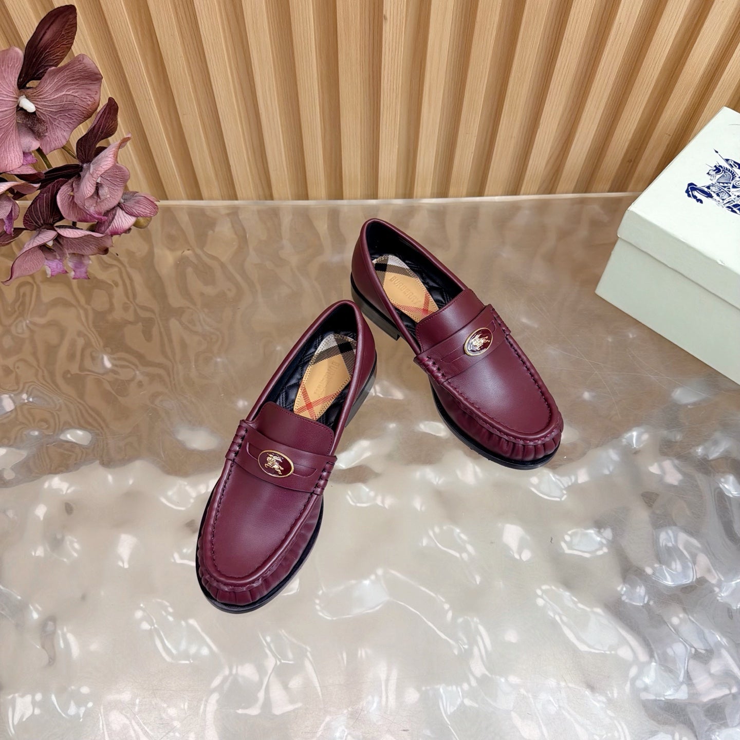 Burgundy leather loafers with gold crest and plaid lining, angled pair view