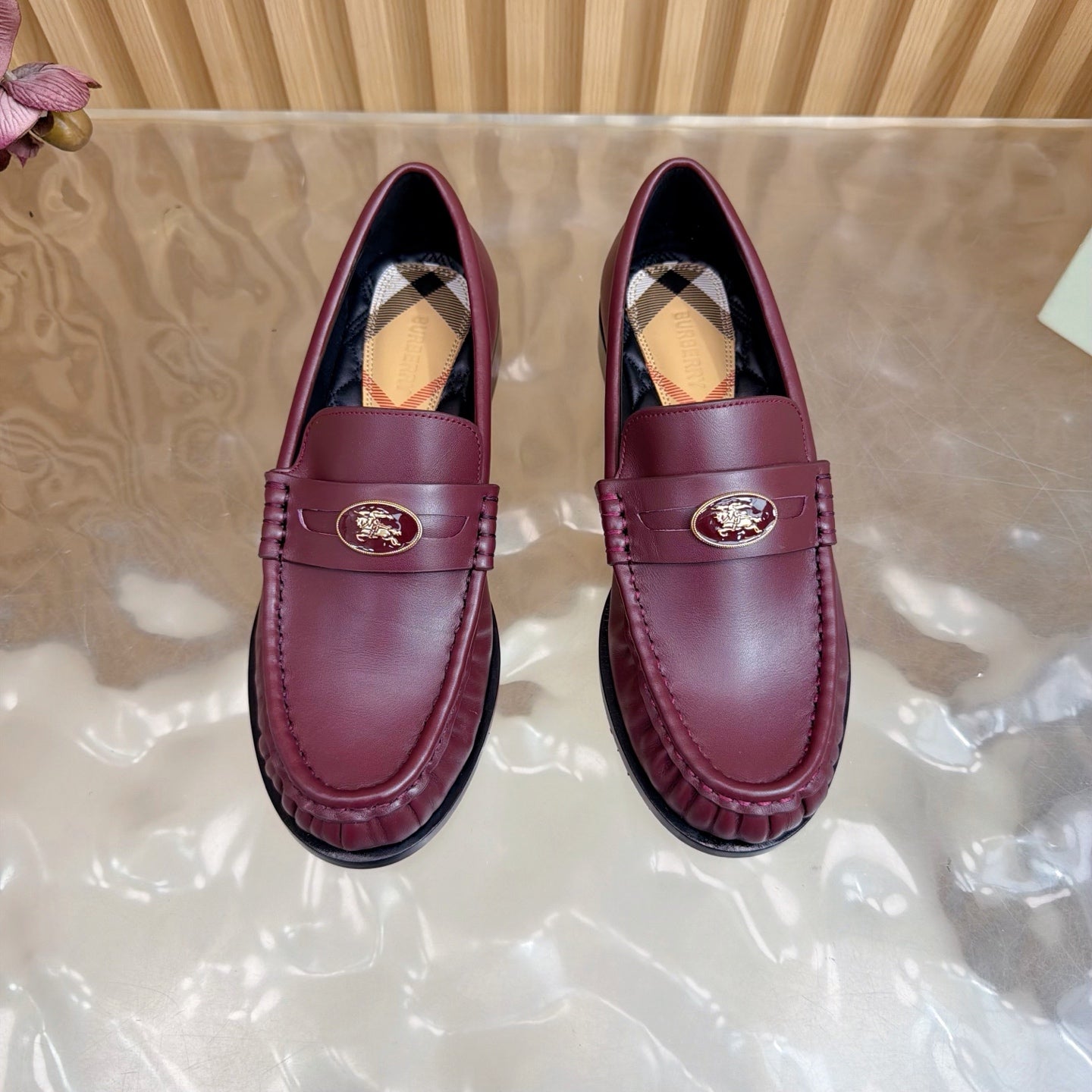 Burgundy leather loafers with gold crest emblem and plaid interior, front close view