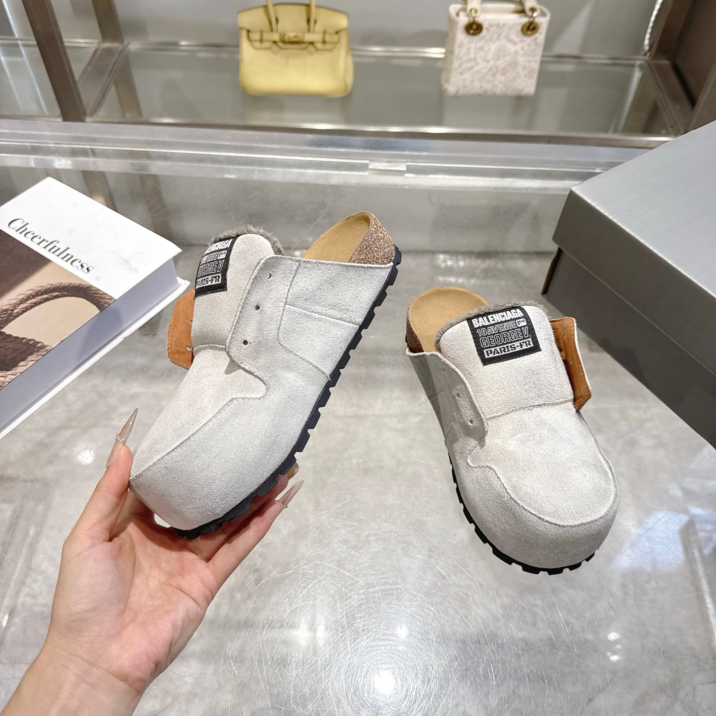 Balenciaga slip-on shoes in light gray suede, angled front view with shearling-lined opening