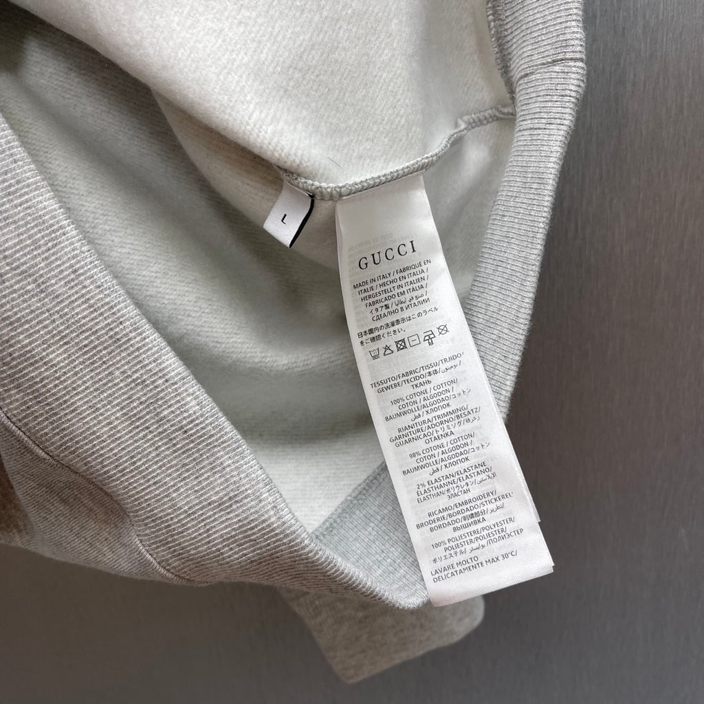 Light gray Gucci sweatshirt care label tag visible inside neckline