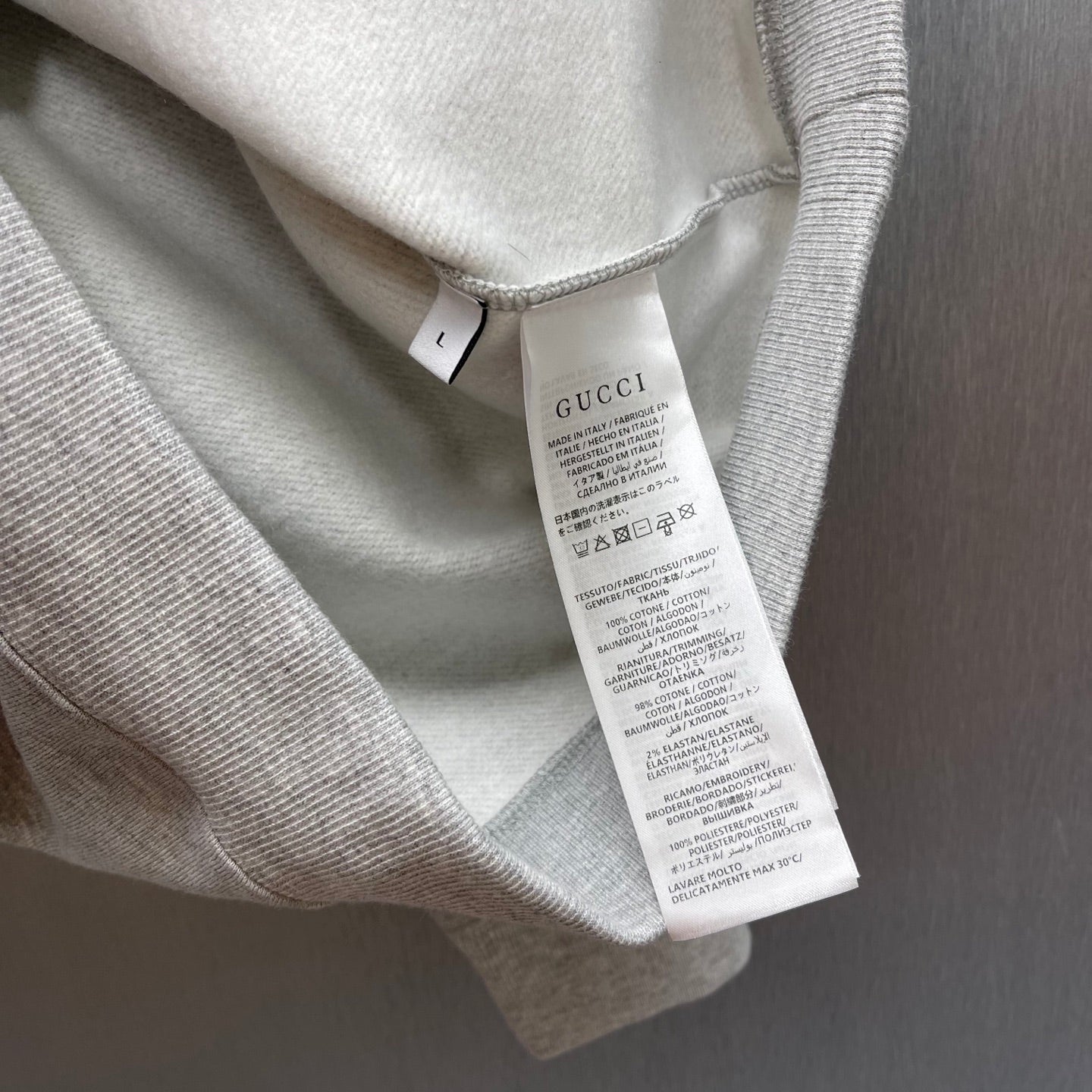 Light gray Gucci sweatshirt care label tag visible inside neckline