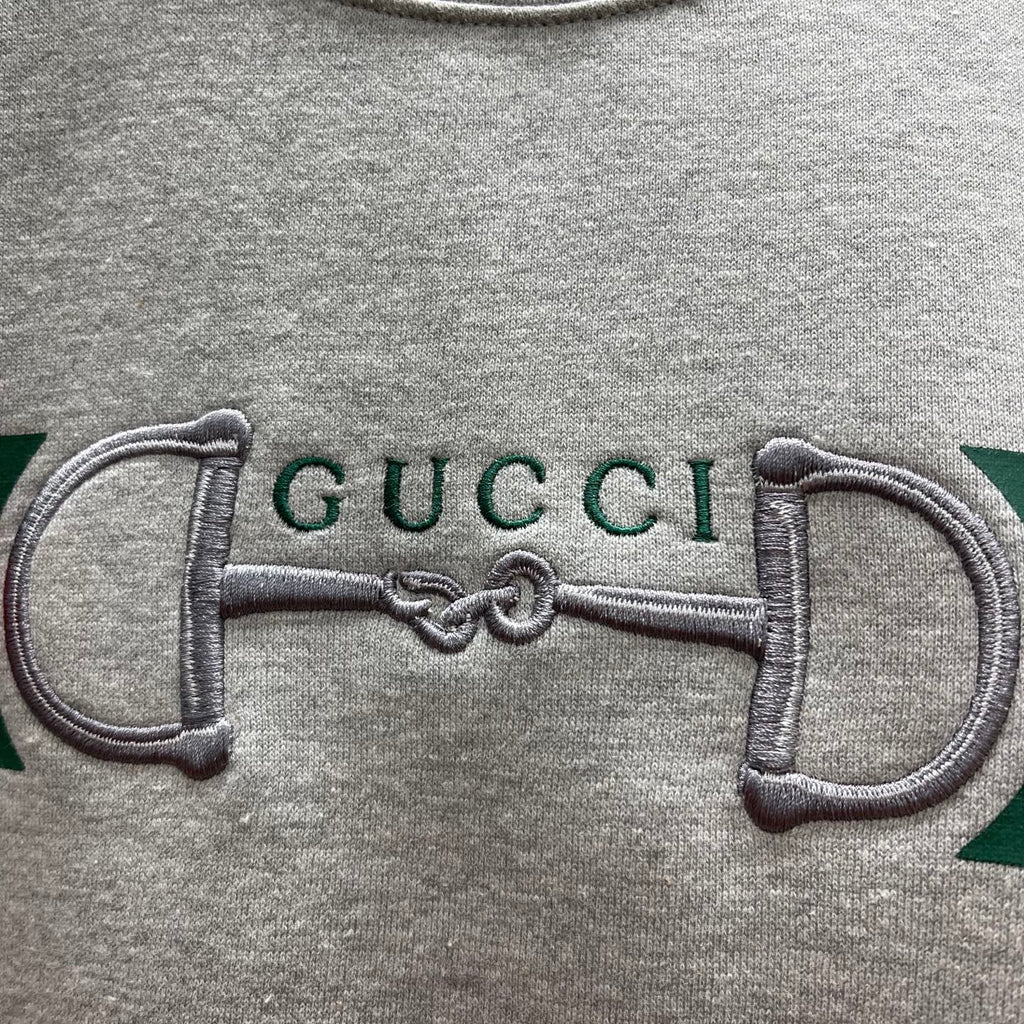 Light gray Gucci sweatshirt close-up of embroidered double-G on stripe panel