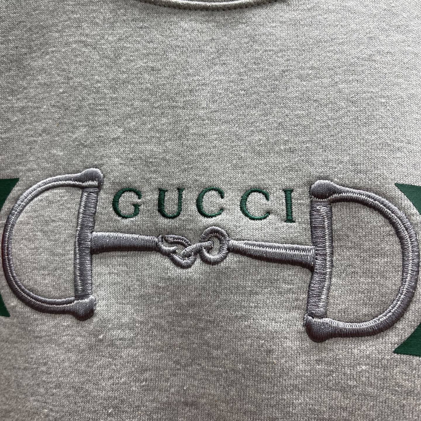 Light gray Gucci sweatshirt close-up of embroidered double-G on stripe panel