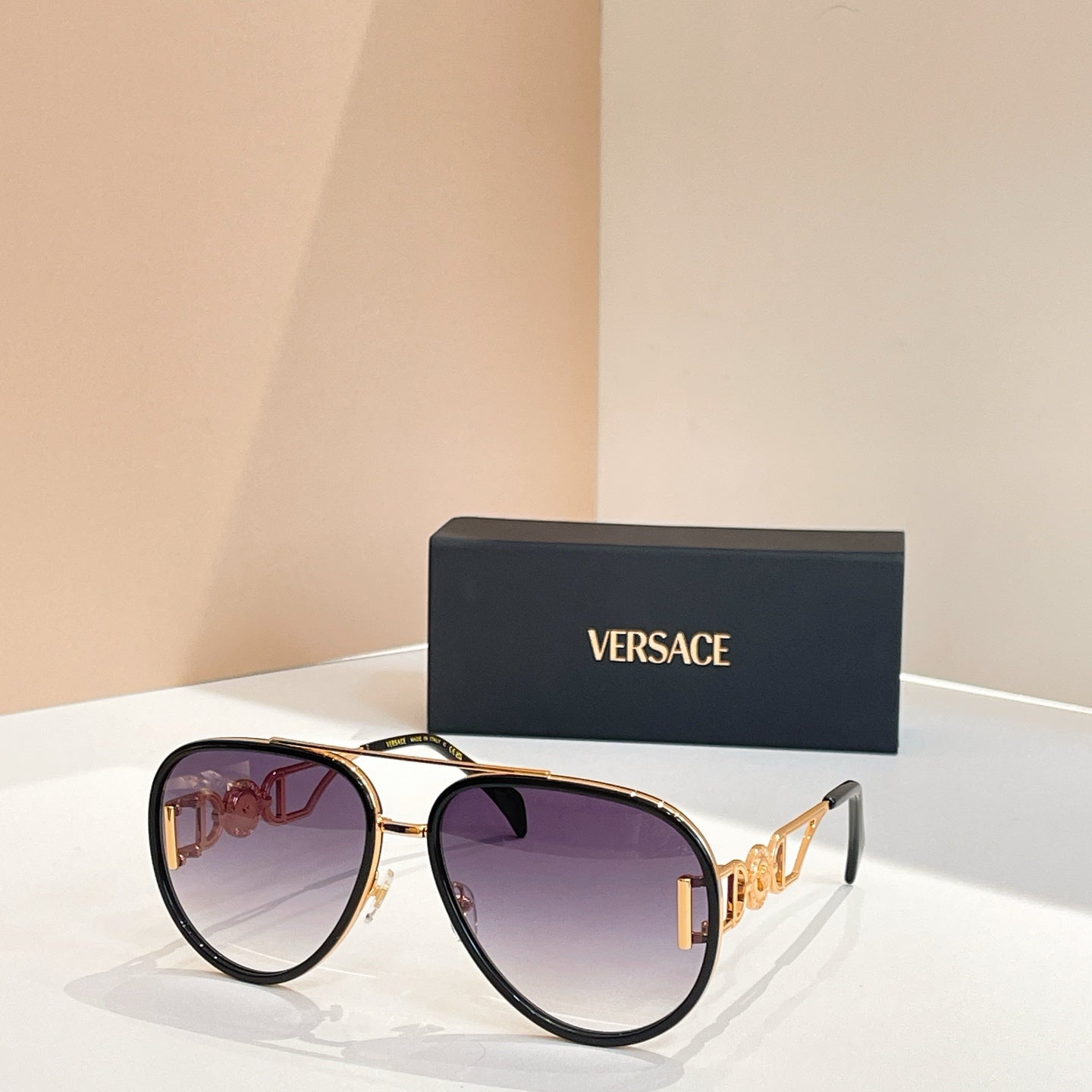 Versace sunglasses with black frames and gold temple tips, purple-tinted lenses