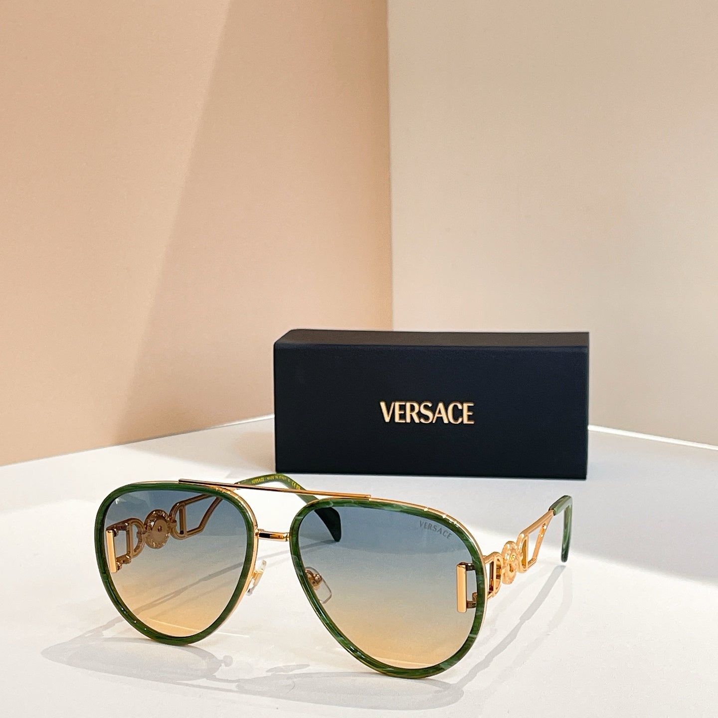 Versace sunglasses with green frames, gold accents, and blue-tinted lenses