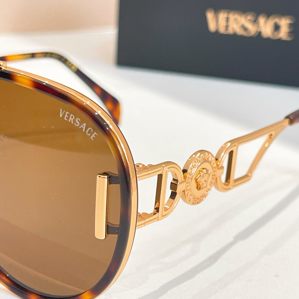 Versace sunglasses close-up with gold frame details and dark-tinted lenses