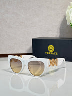 Sunglasses, white frames with gold emblem, tinted light lenses, rounded cat-eye