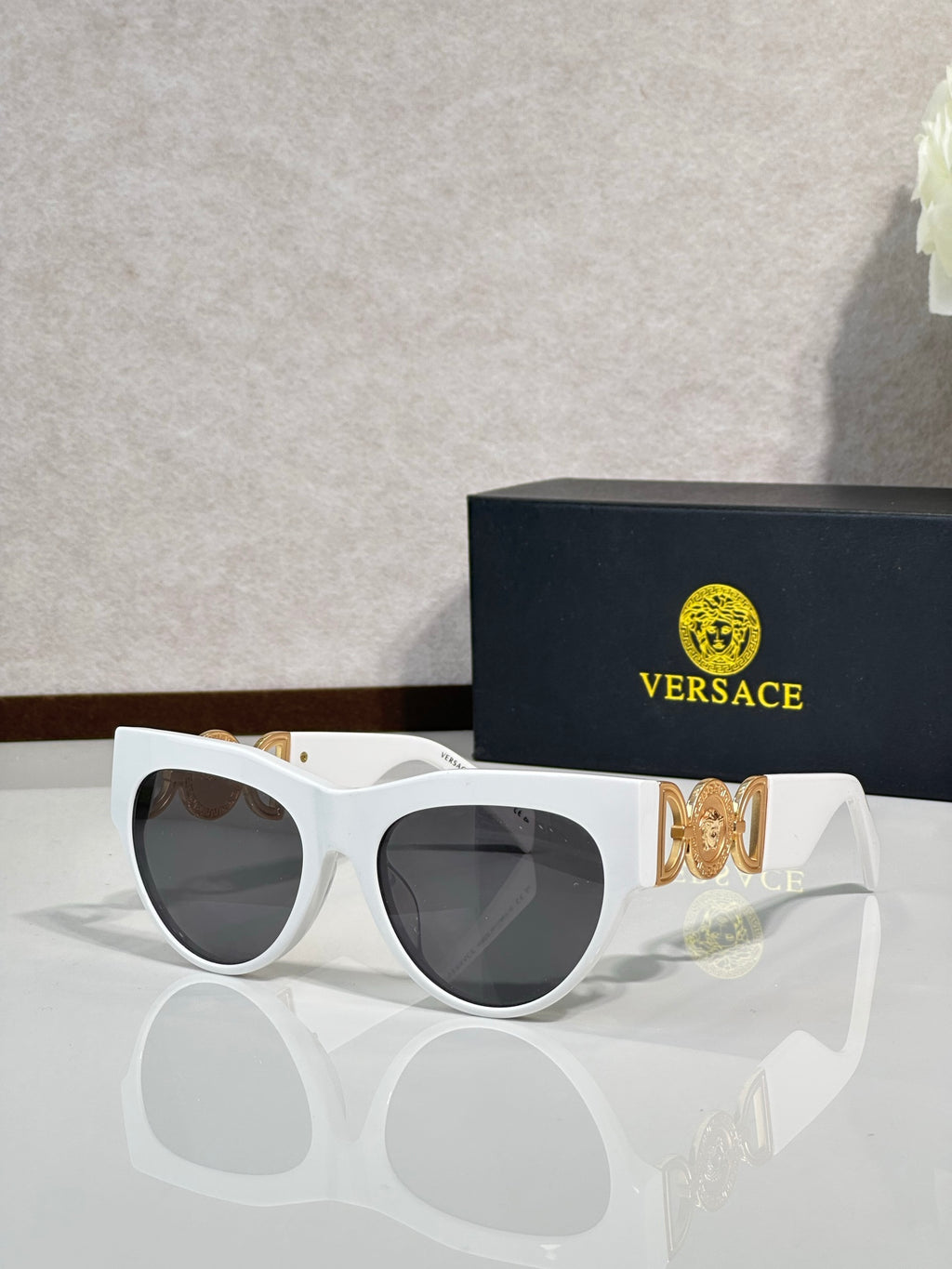 Sunglasses, white frames with gold emblem, tinted dark lenses, cat-eye style