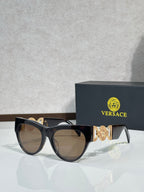 Sunglasses, black frames with gold emblem, tinted brown lenses, cat-eye style