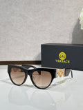 Sunglasses, black frames with gold emblem, tinted brown lenses, cat-eye style