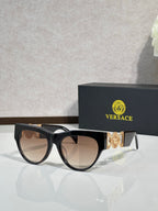 Sunglasses, black frames with gold emblem, tinted brown lenses, cat-eye style