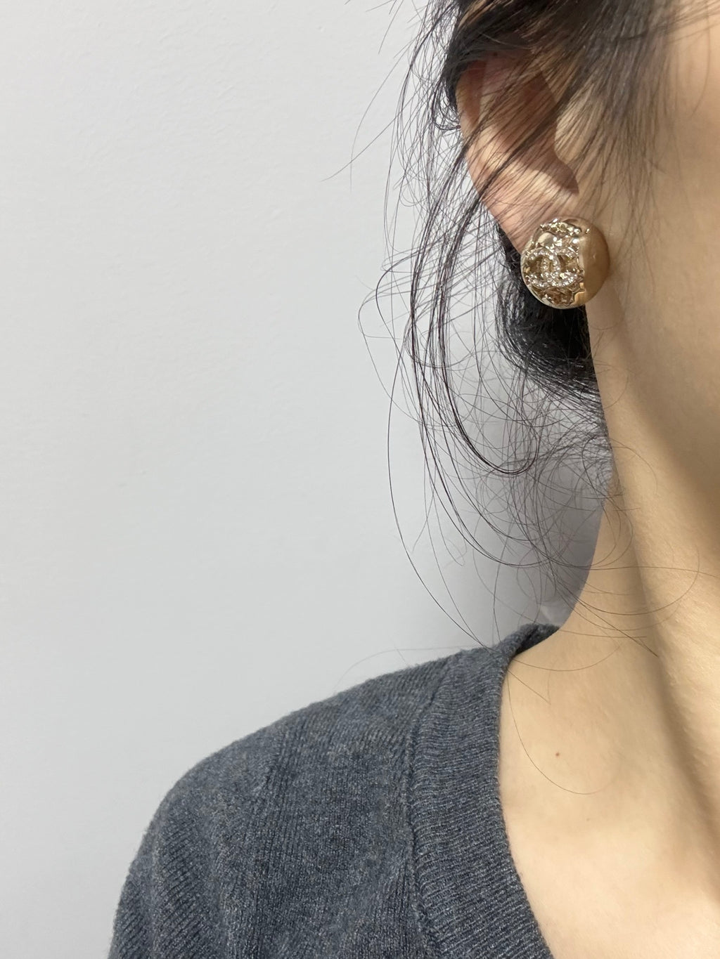 Gold-tone stud earrings with sparkling crystal round motif on the ear