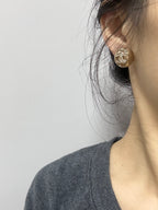 Gold-tone stud earrings with sparkling crystal round motif on the ear