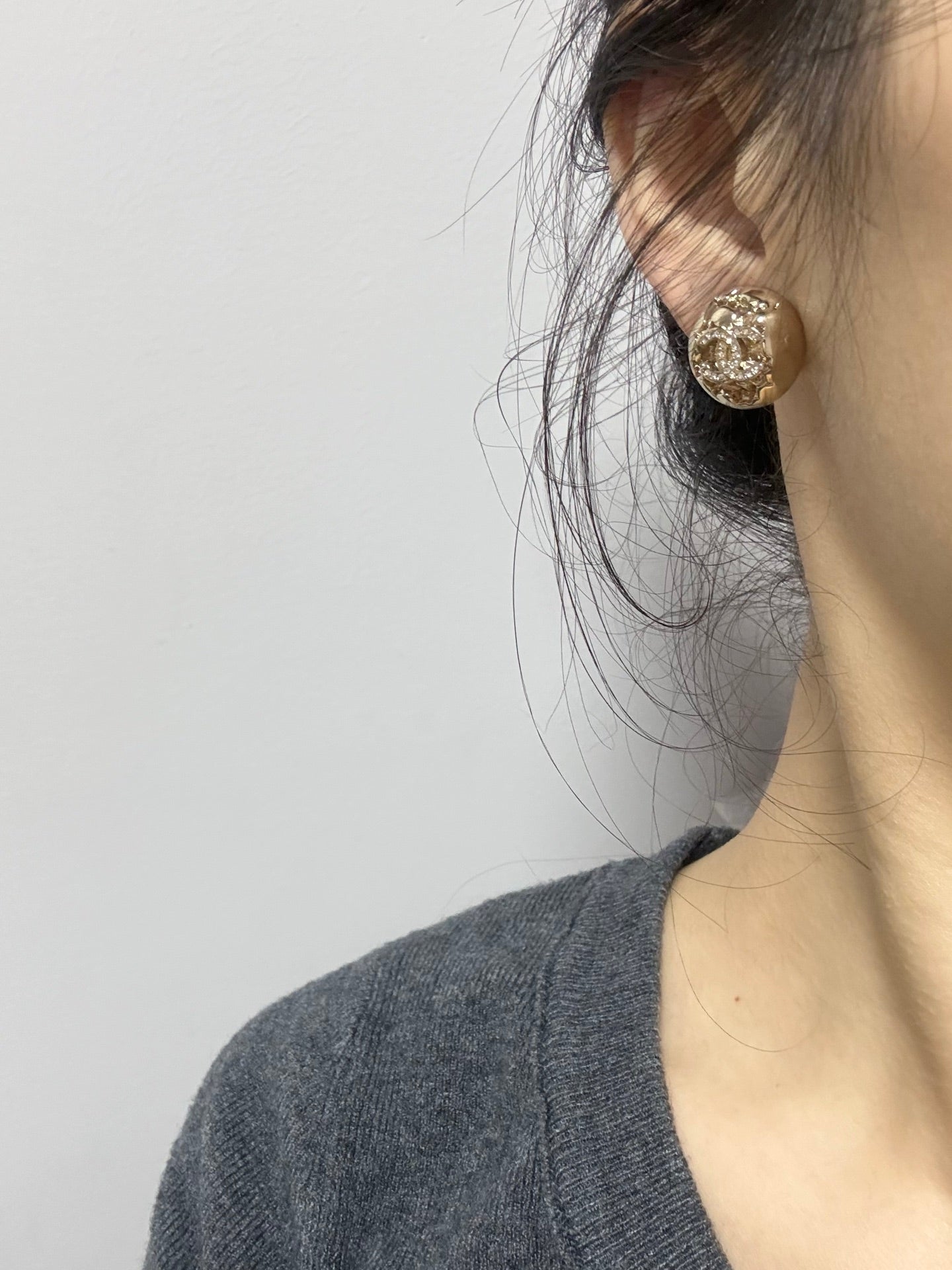 Gold-tone stud earrings with sparkling crystal round motif on the ear