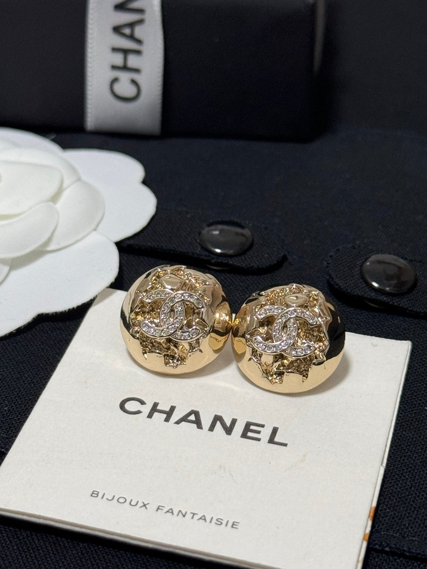 Gold-tone round stud earrings with sparkling crystal halo and logo-style motif
