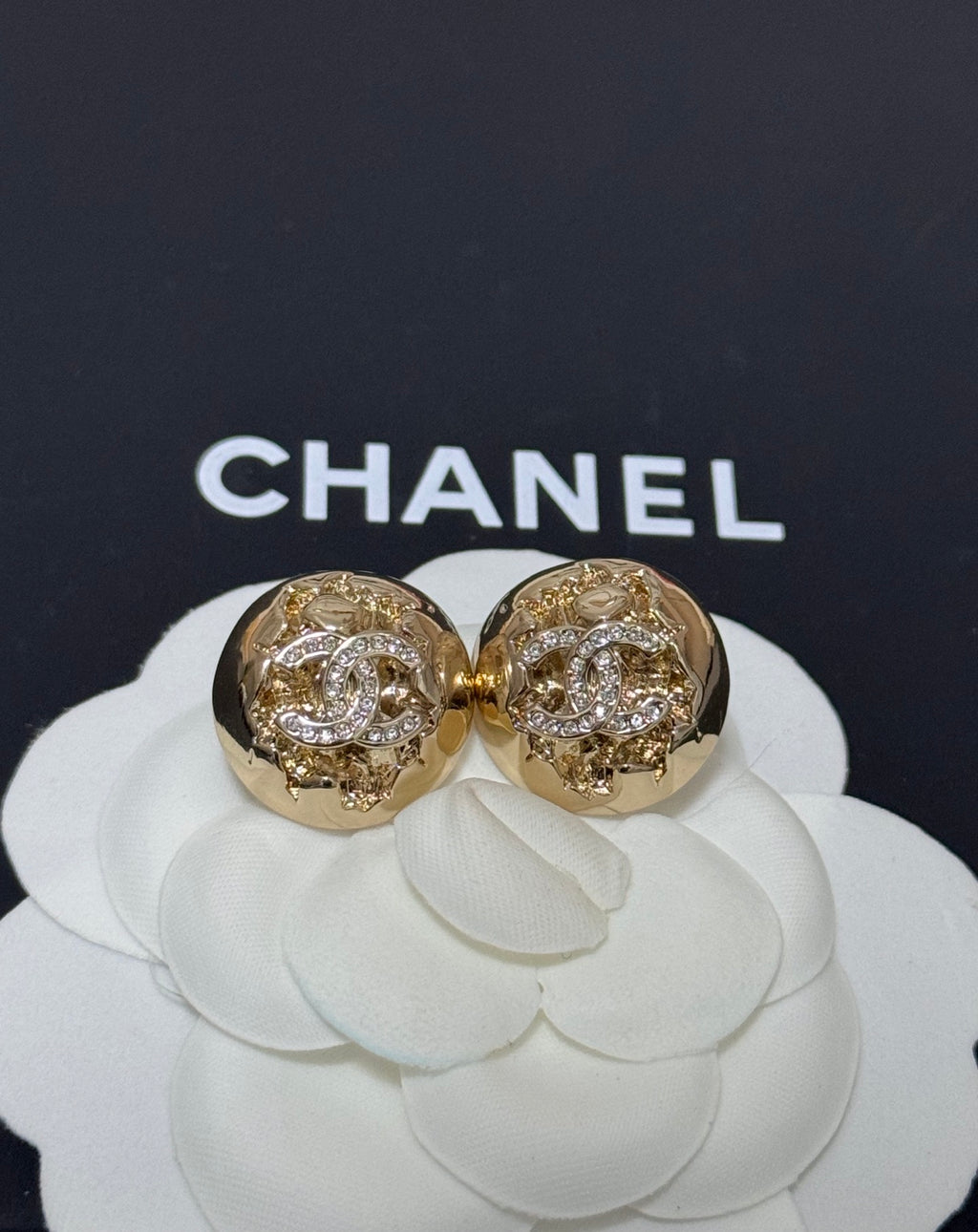 Gold-tone round stud earrings with clear crystal pattern and engraved halo detail