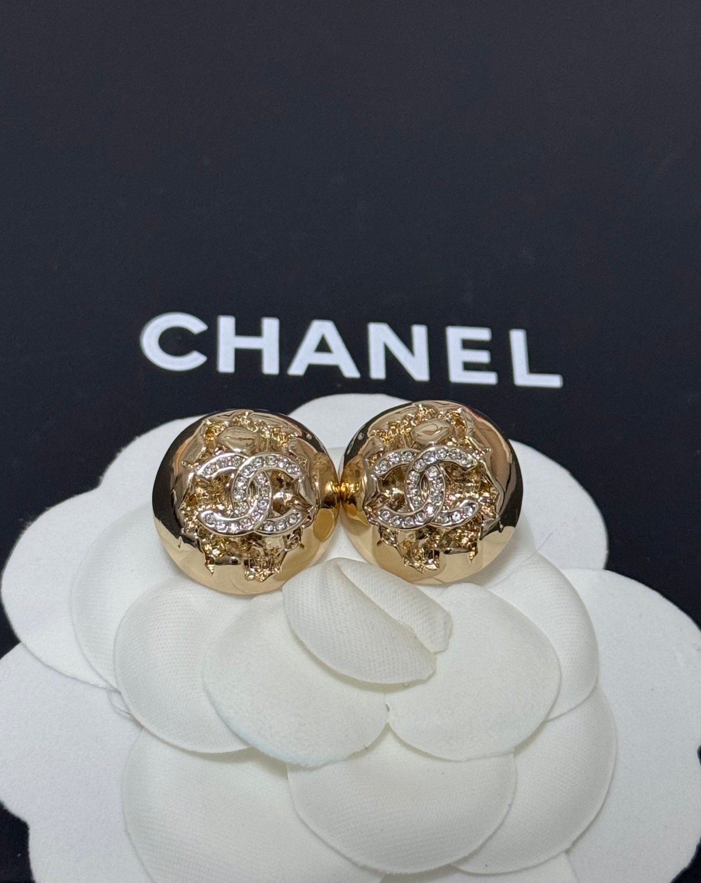 Gold-tone round stud earrings with clear crystal pattern and engraved halo detail