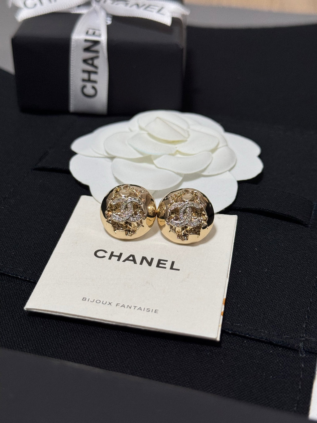 Gold-tone round stud earrings with crystal halo motif on a jewelry card